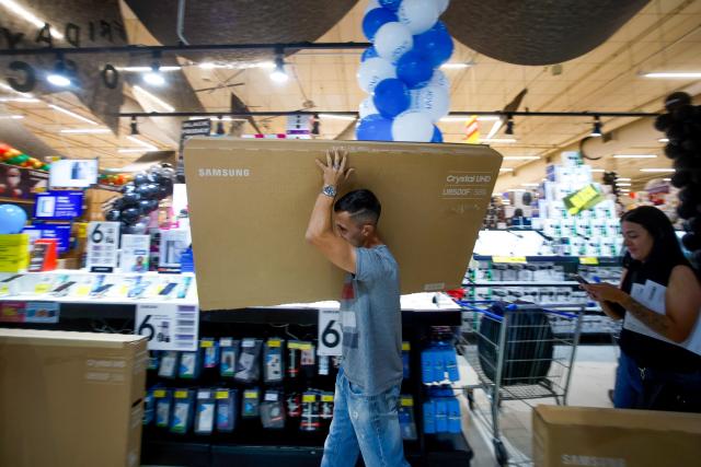 A shopper buys a TV during a Black Friday sale at a supermarket in Sao Paulo, Brazil on November 27, 2025. (Photo by Miguel SCHINCARIOL / AFP)