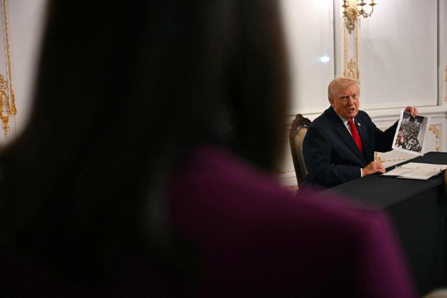 US President Donald Trump shows a printed photo during a video call with military service members from his Mar-a-Lago residence in Palm Beach, Florida, on November 27, 2025, during the Thanksgiving holiday. US President Donald Trump said Thursday that Sarah Beckstrom, one of the two National Guard troops shot a day earlier near the White House, had died, while the other soldier was "fighting for his life." (Photo by Jim WATSON / AFP)