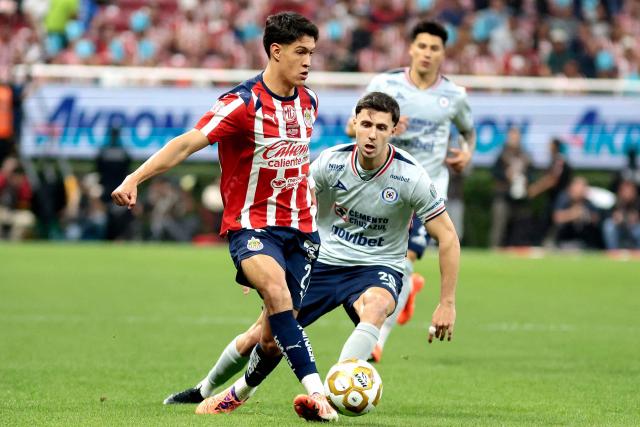 Guadalajara's defender #21 Jose Castillo (L) kicks the ball past Cruz Azul's Argentine forward #20 Jose Paradela (R) during the Liga MX Apertura quarter-final first leg football match between Guadalajara and Cruz Azul at the Akron Stadium in Zapopan, Mexico on November 27, 2025. (Photo by Ulises RUIZ / AFP)