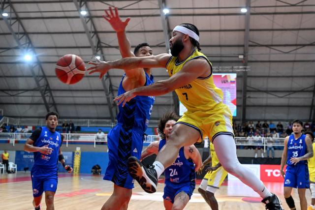 Venezuela's Windi Graterol (L) and Colombia's Romario Roque (R) fight for the ball during the FIBA Basketball World Cup 2027 Americas qualifiers Group C match between Colombia and Venezuela at the Coliseo Evangelista Mora in Cali, Colombia, on November 27, 2025. (Photo by Joaquín SARMIENTO / AFP)