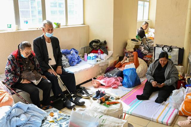 Displaced residents are seen at a makeshift shelter inside a shopping mall near the scene of a major fire that swept through several apartment blocks at the Wang Fuk Court residential estate in Hong Kong's Tai Po district on November 28, 2025. Firefighters searched the last of the housing estate flats torched by Hong Kong's worst fire in decades on November 28, with the death toll rising to at least 94 overnight and scores still missing. (Photo by Peter PARKS / AFP)