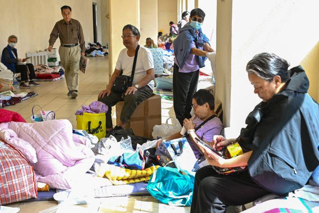 Displaced residents are seen at a makeshift shelter inside a shopping mall near the scene of a major fire that swept through several apartment blocks at the Wang Fuk Court residential estate in Hong Kong's Tai Po district on November 28, 2025. Firefighters searched the last of the housing estate flats torched by Hong Kong's worst fire in decades on November 28, with the death toll rising to at least 94 overnight and scores still missing. (Photo by Peter PARKS / AFP)