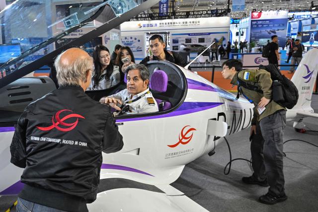 A man sits in the cockpit of an airplane at the Jiangsu Shengyi Aviation Technology booth during the Aero Asia 2025 in Zhuhai, in southern China's Guangdong province on November 28, 2025. Aero Asia 2025 is an international aviation and aerospace exhibition that runs between November 27 and 30. (Photo by Hector RETAMAL / AFP)