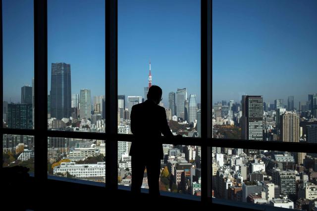 A man looks out the window at the view from a high-rise building in Tokyo on November 28, 2028. (Photo by Kazuhiro NOGI / AFP)