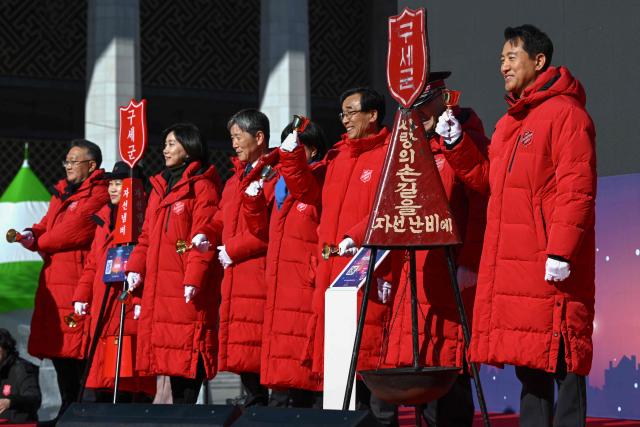 Seoul Mayor Oh Se-hoon (R) and other attendees ring their bells beside a charity pot during a ceremony to launch a year-end fundraising campaign of the Salvation Army at Gwanghwamun square in Seoul on November 28, 2025. (Photo by Jung Yeon-je / AFP)