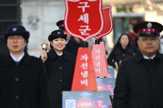 Salvation Army officers ring bells besides a charity pot during a ceremony to launch a year-end fundraising campaign of the Salvation Army at Gwanghwamun square in Seoul on November 28, 2025. (Photo by Jung Yeon-je / AFP)
