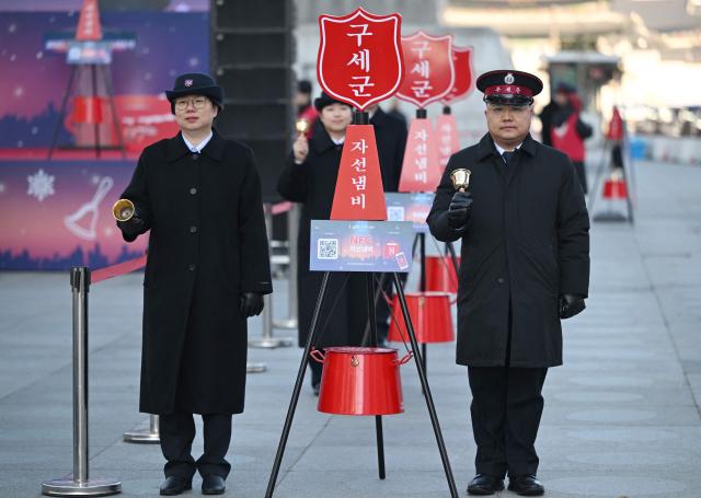 Salvation Army officers ring bells besides a charity pot during a ceremony to launch a year-end fundraising campaign of the Salvation Army at Gwanghwamun square in Seoul on November 28, 2025. (Photo by Jung Yeon-je / AFP)