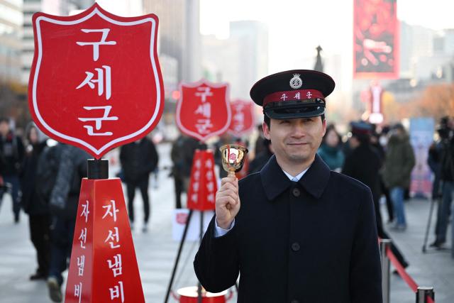 A Salvation Army officer rings a bell besides a charity pot during a ceremony to launch a year-end fundraising campaign of the Salvation Army at Gwanghwamun square in Seoul on November 28, 2025. (Photo by Jung Yeon-je / AFP)