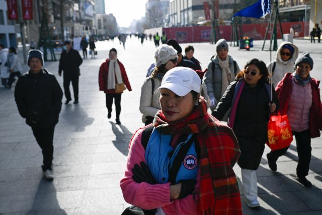 A group of tourists visits a shopping street in Beijing on November 28, 2025. (Photo by WANG Zhao / AFP)
