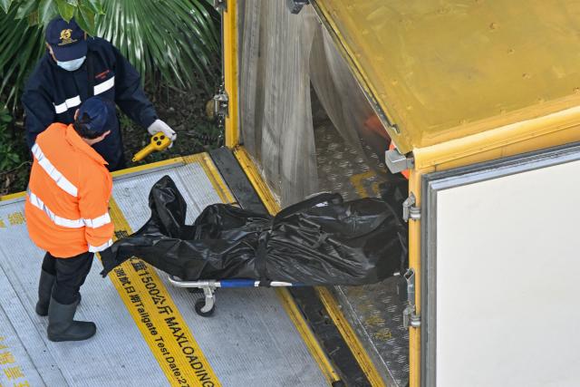 EDITORS NOTE: Graphic content / A body is transferred into a vehicle in the aftermath of a major fire that swept through several apartment blocks at the Wang Fuk Court residential estate in Hong Kong's Tai Po district on November 28, 2025. Families of the scores still missing after Hong Kong's worst blaze in decades scoured hospitals on November 28 as firefighting operations ended, with the death toll at least 94. (Photo by Peter PARKS / AFP)