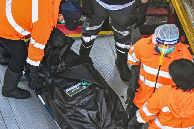 EDITORS NOTE: Graphic content / TOPSHOT - A body is transferred into a vehicle in the aftermath of a major fire that swept through several apartment blocks at the Wang Fuk Court residential estate in Hong Kong's Tai Po district on November 28, 2025. Families of the scores still missing after Hong Kong's worst blaze in decades scoured hospitals on November 28 as firefighting operations ended, with the death toll at least 94. (Photo by Peter PARKS / AFP)