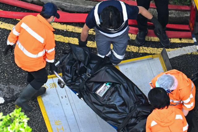 EDITORS NOTE: Graphic content / A body is transferred into a vehicle in the aftermath of a major fire that swept through several apartment blocks at the Wang Fuk Court residential estate in Hong Kong's Tai Po district on November 28, 2025. Families of the scores still missing after Hong Kong's worst blaze in decades scoured hospitals on November 28 as firefighting operations ended, with the death toll at least 94. (Photo by Peter PARKS / AFP)