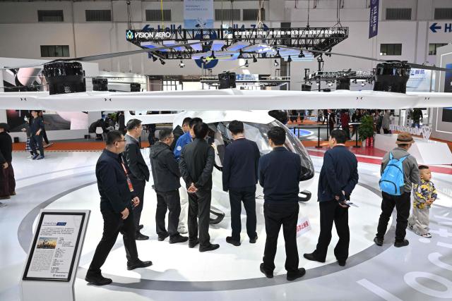 People look at a VoloCity eVolt aircraft seen in the Volocopter booth during the Aero Asia 2025 in Zhuhai, in southern China's Guangdong province on November 28, 2025. Aero Asia 2025 is an international aviation and aerospace exhibition that runs between November 27 and 30. (Photo by Hector RETAMAL / AFP)