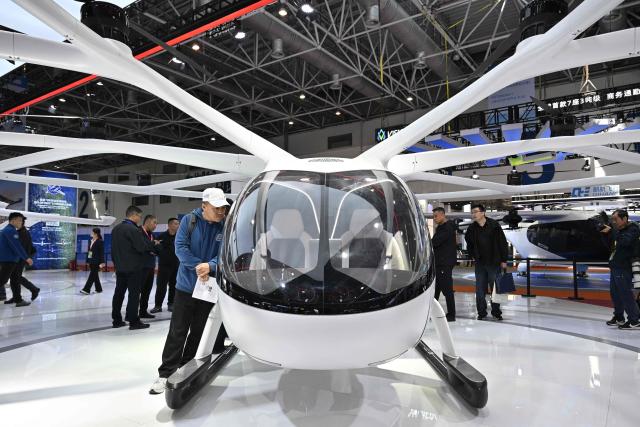 People look at a VoloCity eVolt aircraft seen in the Volocopter booth during the Aero Asia 2025 in Zhuhai, in southern China's Guangdong province on November 28, 2025. Aero Asia 2025 is an international aviation and aerospace exhibition that runs between November 27 and 30. (Photo by Hector RETAMAL / AFP)
