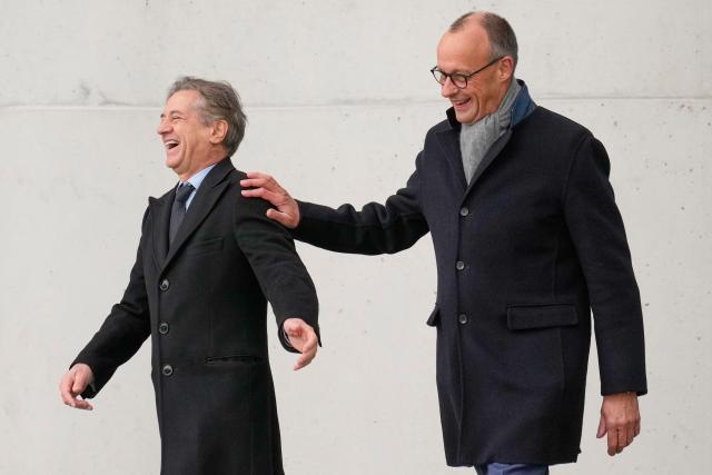 German Chancellor Friedrich Merz (L) and Slovenia's Prime Minister Robert Golob share a lough as they arrive on the balcony of the Chancellery prior talks in Berlin, Germany, on November 28, 2025.  (Photo by Ebrahim Noroozi / POOL / AFP)