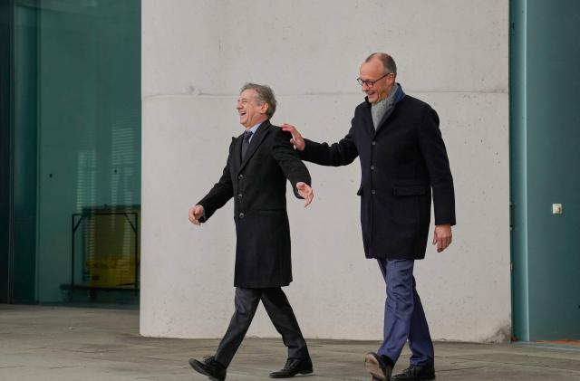 German Chancellor Friedrich Merz (L) and Slovenia's Prime Minister Robert Golob share a lough as they arrive on the balcony of the Chancellery prior talks in Berlin, Germany, on November 28, 2025.  (Photo by Ebrahim Noroozi / POOL / AFP)