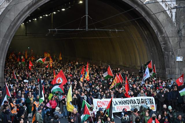 People march behind a banner reading "Against the war maneuver, for wages, pensions and social rights" during a pro-Palestinian demonstration as part of the nationwide General Strike against Italy's government, in Genoa on November 28, 2025 (Photo by Piero CRUCIATTI / AFP)
