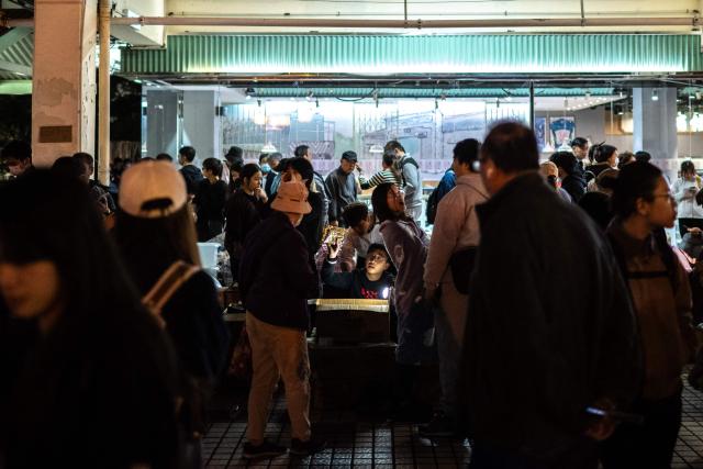 Crowds distribute daily necessities after a major fire that swept through several apartment blocks at the Wang Fuk Court residential estate in Hong Kong's Tai Po district on November 28, 2025. The death toll from Hong Kong's worst blaze in decades rose to 128, with dozens still missing, as authorities said fire alarms in the residential estate buildings had been malfunctioning. (Photo by Philip FONG / AFP)