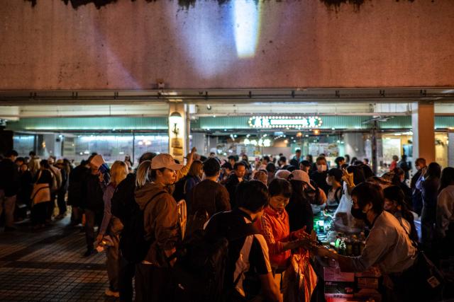 Crowds distribute daily necessities after a major fire that swept through several apartment blocks at the Wang Fuk Court residential estate in Hong Kong's Tai Po district on November 28, 2025. The death toll from Hong Kong's worst blaze in decades rose to 128, with dozens still missing, as authorities said fire alarms in the residential estate buildings had been malfunctioning. (Photo by Philip FONG / AFP)