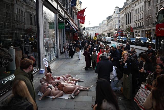 Members of the public make their way past protesters from animal rights group PETA, promoting their "Free the Animals Friday" campaign, outside a luxury brand shop in London on November 28, 2025. (Photo by HENRY NICHOLLS / AFP)