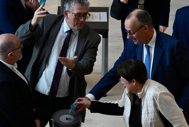 German Chancellor Friedrich Merz (R) casts his ballot for the federal budget 2026 during a debate on the 2026 federal budget at the Bundestag (lower house of parliament) on November 28, 2025 in Berlin. (Photo by John MACDOUGALL / AFP)