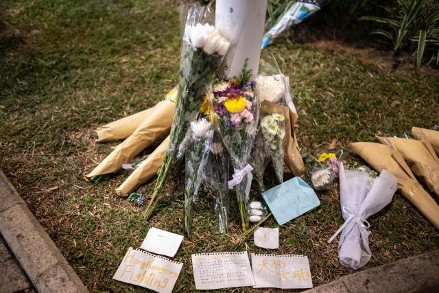 Flowers and messages are left at the aftermath of a major fire that swept through several apartment blocks at the Wang Fuk Court residential estate in Hong Kong's Tai Po district on November 28, 2025. The death toll from Hong Kong's worst blaze in decades rose to 128 on november 28, with dozens still missing, as authorities said fire alarms in the residential estate buildings had been malfunctioning. (Photo by Philip FONG / AFP)