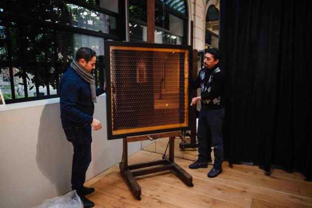 Employees install a chocolate pastry made by France's pastry chef Jerome de Oliveira displayed on November 28, 2025 in Paris three days ahead of an auction of 25 grands chefs pastries for the benefit of the BAB Charity association, which works for the well-being and development of children with leukaemia who are hospitalised at the Armand Trousseau Hospital in Paris. (Photo by Dimitar DILKOFF / AFP)
