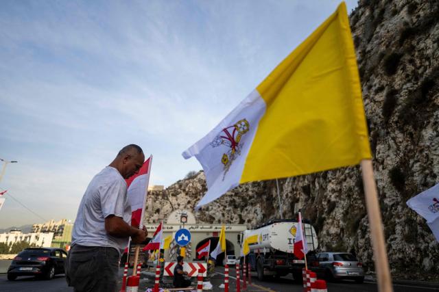Workers install Vatican and Lebanese flags along a highway in Zouk Mosbeh on the outskirts of Beirut on November 28, 2025, ahead of Pope Leo XIV’s visit to Lebanon. In his first trip abroad since becoming head of the Catholic Church, US-born Pope Leo XIV is travelling to Turkey and Lebanon, arriving in Beirut on November 30. (Photo by Jewel SAMAD / AFP)
