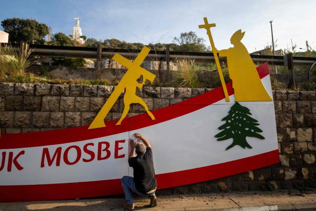 A man installs a sign beside a highway in Zouk Mosbeh on the outskirts of Beirut on November 28, 2025, ahead of Pope Leo XIV’s visit to Lebanon. In his first trip abroad since becoming head of the Catholic Church, US-born Pope Leo XIV is travelling to Turkey and Lebanon, arriving in Beirut on November 30. (Photo by Jewel SAMAD / AFP)