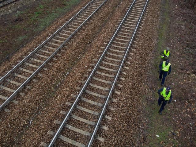 Two guards of the Railway Security Guard and a soldier of the Territorial Defense Forces patrol the area along the railroad tracks in the suburbs of Warsaw on November 27, 2025. The patrol is a part of "Operation Horizon," an effort launched by Poland earlier this month designed to boost rail security and protect critical infrastructure, following a series of diversions, which officials blame on Russia. (Photo by Wojtek RADWANSKI / AFP)