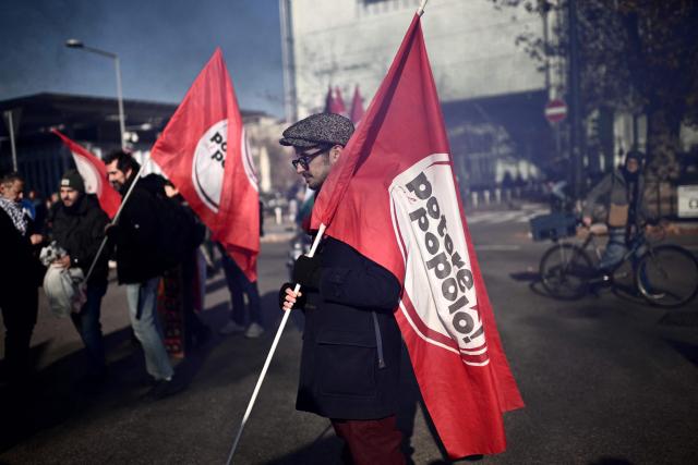 Protesters hold flags "Potere al Popolo" (Power to people) during a nationwide strike organized by the Unione Sindacale di Base (USB Union) in Turin, northwestern Italy on November 28, 2025. Trade unions have called a strike for public and private sector workers, affecting transport, schools, healthcare, and other public services. The reasons behind the strike are linked to the 2026 Economic Plan, which is being contested by the union groups CUB, USB, SGB, COBAS, and USI-CIT, who oppose the increase in military spending at the expense of essential public services. (Photo by MARCO BERTORELLO / AFP)
