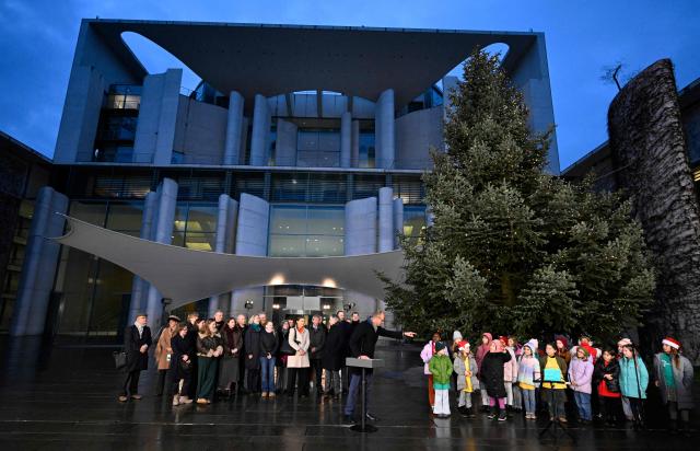 German Chancellor Friedrich Merz (C) talks with children during an official event to hand over the Christmas tree for the Chancellery, on November 28, 2025 in front of the Chancellery in Berlin. (Photo by Tobias SCHWARZ / AFP)