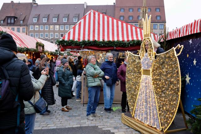 A visitor poses for photos at the Christmas market prior to its official opening in Nuremberg, Germany on November 28, 2025.  (Photo by Alexandra BEIER / AFP)
