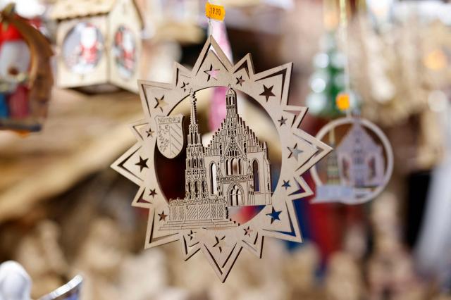 A wooden Christmas star showing the city's Church of Our Lady and the Gothic Beautiful Fountain (Schoener Brunnen) is diplayed at a stall at the Christmas market prior to its official opening in Nuremberg, Germany on November 28, 2025.  (Photo by Alexandra BEIER / AFP)