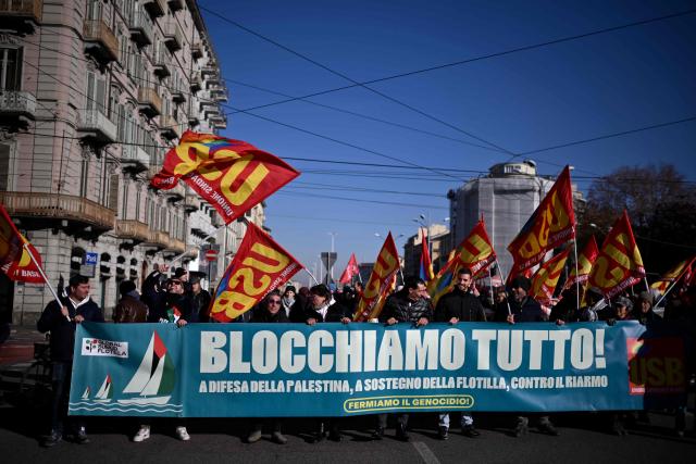 People march behind a banner "Let's block everything" during a nationwide strike organized by the Unione Sindacale di Base (USB Union) in Turin, northwestern Italy on November 28, 2025. Trade unions have called a strike for public and private sector workers, affecting transport, schools, healthcare, and other public services. The reasons behind the strike are linked to the 2026 Economic Plan, which is being contested by the union groups CUB, USB, SGB, COBAS, and USI-CIT, who oppose the increase in military spending at the expense of essential public services. (Photo by MARCO BERTORELLO / AFP)
