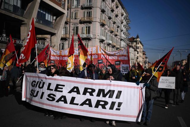 People march behind a banner "down weapons on wages" during a nationwide strike organized by the Unione Sindacale di Base (USB Union) in Turin, northwestern Italy on November 28, 2025. Trade unions have called a strike for public and private sector workers, affecting transport, schools, healthcare, and other public services. The reasons behind the strike are linked to the 2026 Economic Plan, which is being contested by the union groups CUB, USB, SGB, COBAS, and USI-CIT, who oppose the increase in military spending at the expense of essential public services. (Photo by MARCO BERTORELLO / AFP)