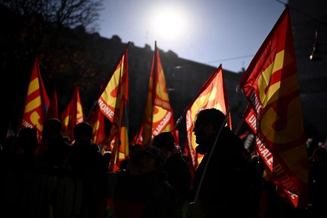 People march with USB flags during a nationwide strike organized by the Unione Sindacale di Base (USB Union) in Turin, northwestern Italy on November 28, 2025. Trade unions have called a strike for public and private sector workers, affecting transport, schools, healthcare, and other public services. The reasons behind the strike are linked to the 2026 Economic Plan, which is being contested by the union groups CUB, USB, SGB, COBAS, and USI-CIT, who oppose the increase in military spending at the expense of essential public services. (Photo by MARCO BERTORELLO / AFP)