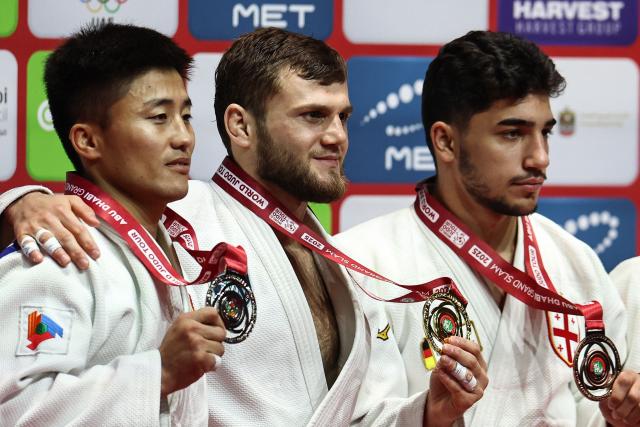 From left, silver medallist Mongolia's Ariunbold Enkhtaivan, gold medallist Russia's Ayub Bliev and bronze medallist Georgia's Giorgi Sardalashvili stand on the podium during the award ceremony for the men's under 60 kg category during the Abu Dhabi Grand Slam tournament, in Abu Dhabi, on November 28, 2025. The Russian judo federation hailed "a historic decision" after the sport's global governing body announced on November 27, that their judokas are once again free to compete "under their national flag". But Ukraine's national judo federation blasted a decision which was contrary to "peace, justice, and responsibility" and vowed to "take all possible measures to prevent" its implementation. (Photo by Fadel SENNA / AFP)