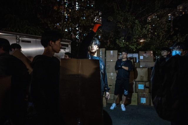 Volunteers form a human chain to move the boxes of goods away from the area near the aftermath of a major fire that swept through several apartment blocks at the Wang Fuk Court residential estate in Hong Kong's Tai Po district on November 28, 2025. The raging fire at Wang Fuk Court claimed at least 128 lives in what was the world's deadliest residential building fire since 1980, and authorities said Friday the status of around 200 people remained "unclear". (Photo by Philip FONG / AFP)