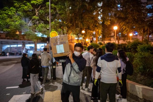 Volunteers form a human chain to move the boxes of goods away from the area near the aftermath of a major fire that swept through several apartment blocks at the Wang Fuk Court residential estate in Hong Kong's Tai Po district on November 28, 2025. The raging fire at Wang Fuk Court claimed at least 128 lives in what was the world's deadliest residential building fire since 1980, and authorities said Friday the status of around 200 people remained "unclear". (Photo by Philip FONG / AFP)