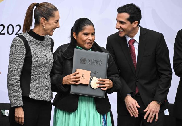 Tarahumara ethnic long-distance and ultramarathon runner Maria Lorena Ramirez (C) poses with Mexico's President Claudia Sheinbaum and the Director of the National Commission for Physical Culture and Sport Rommel Pacheco after receiving the National Sports Award during a ceremony at the National Palace in Mexico City on November 28, 2025. (Photo by Yuri CORTEZ / AFP)