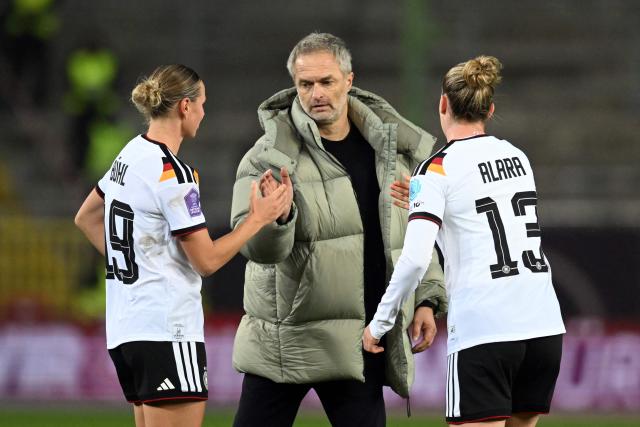 Germany's head coach Christian Wueck reacts with players Germany's midfielder #13 Alara Sehitler (R) and Germany's midfielder #19 Klara Buehl after the UEFA Women's Nations League first leg final football match between Germany and Spain in Kaiserslautern, western Germany on November 28, 2025. The match ended in a 0-0 draw. (Photo by THOMAS KIENZLE / AFP)