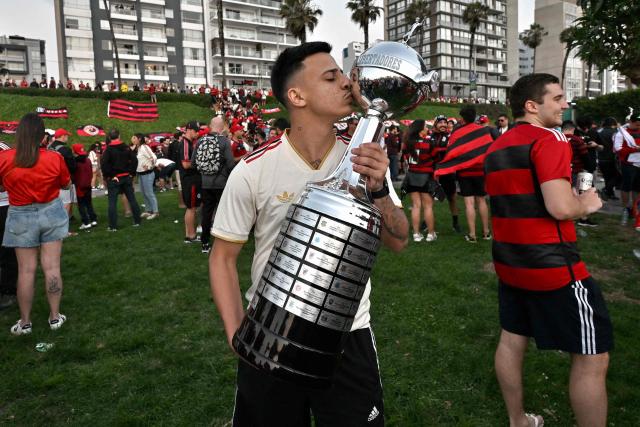A fans of Flamengo kisses a replica of the Copa Libertadores trophy on the eve of the Copa Libertadores final football match between Brazil's Palmeiras and Flamengo at Maria Reiche park in Lima on November 28, 2025. (Photo by Luis ACOSTA / AFP)