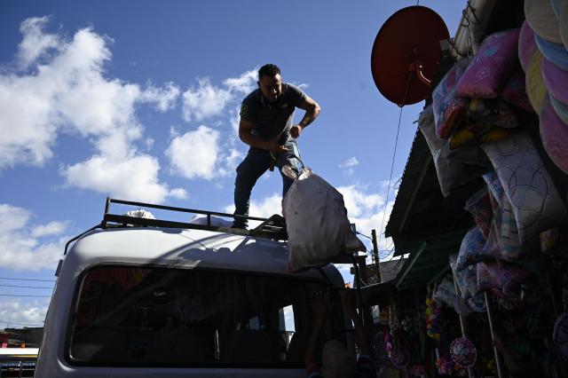 A man loads groceries on a car at the Belen market in Tegucigalpa on November 28, 2025. Honduras will hold presidential elections on November 30. (Photo by Orlando SIERRA / AFP)