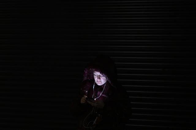 A woman uses her mobile phone as she takes shelter at a metro station during an air attack in Kyiv on November 29, 2025, amid the Russian invasion of Ukraine. Loud explosions were heard in the Ukrainian capital Kyiv early on November 29, 2025, the mayor and AFP journalists said. (Photo by Sergei GAPON / AFP)