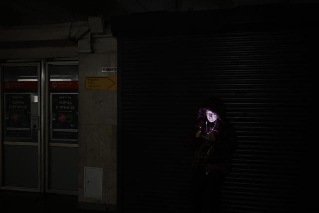 A woman uses her mobile phone as she takes shelter at a metro station during an air attack in Kyiv on November 29, 2025, amid the Russian invasion of Ukraine. Loud explosions were heard in the Ukrainian capital Kyiv early on November 29, 2025, the mayor and AFP journalists said. (Photo by Sergei GAPON / AFP)