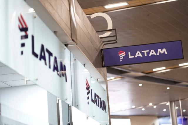 The Latam Airlines logo is pictured at El Dorado airport in Bogota on November 28, 2025. The International Air Transport Association (IATA) urged Venezuela on November 27 to "reconsider" the revocation of concessions for six airlines that canceled their flights following a security alert issued by the United States. The measure affected Spain's Iberia, Portugal's TAP, Colombia's Avianca, the Colombian subsidiary of Chilean-Brazilian Latam, Brazil's GOL and Turkey's Turkish Airlines, which had suspended their connections with Venezuela after Washington issued an alert over military activity in the southern Caribbean. (Photo by Sergio Yate / AFP)