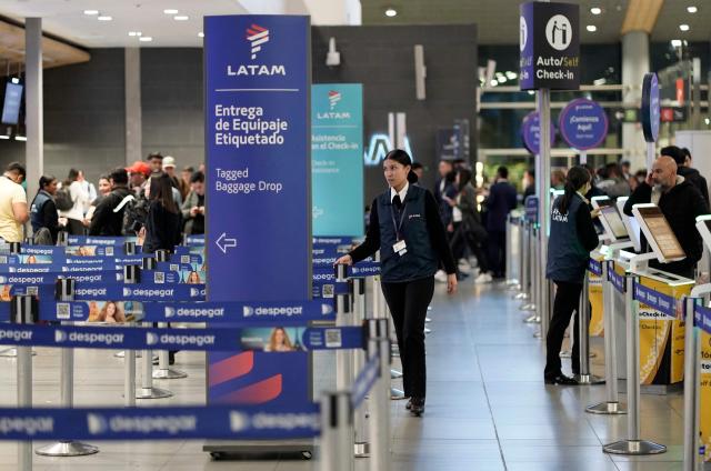 Passengers check in at Latam Airlines counters at El Dorado airport in Bogota on November 28, 2025. The International Air Transport Association (IATA) urged Venezuela on November 27 to "reconsider" the revocation of concessions for six airlines that canceled their flights following a security alert issued by the United States. The measure affected Spain's Iberia, Portugal's TAP, Colombia's Avianca, the Colombian subsidiary of Chilean-Brazilian Latam, Brazil's GOL and Turkey's Turkish Airlines, which had suspended their connections with Venezuela after Washington issued an alert over military activity in the southern Caribbean. (Photo by Sergio Yate / AFP)