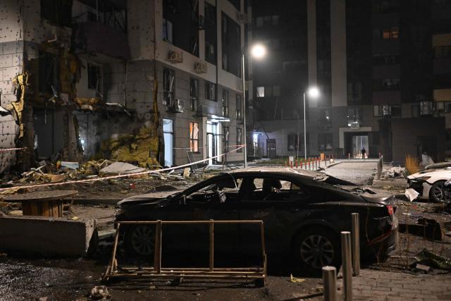 A local resident walks in the courtyard of a damaged residential building following a drone attack in Kyiv on November 29, 2025, amid the Russian invasion in Ukraine. A Russian drone attack targeted the Ukrainian capital in the early hours of November 29, 2025, wounding seven people, authorities in Kyiv said. (Photo by Sergei GAPON / AFP)