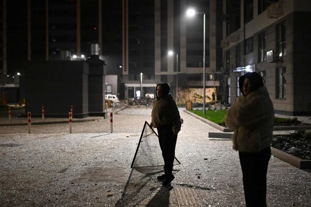 Local resident stand in the courtyard of a damaged residential building following a drone attack in Kyiv on November 29, 2025, amid the Russian invasion in Ukraine. A Russian drone attack targeted the Ukrainian capital in the early hours of November 29, 2025, wounding seven people, authorities in Kyiv said. (Photo by Sergei GAPON / AFP)